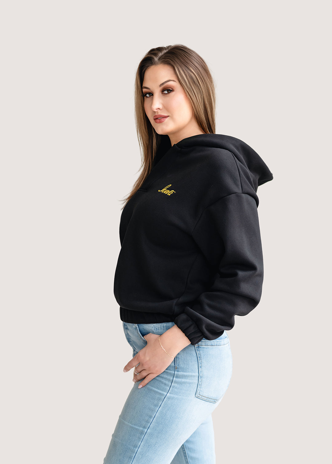 Woman wearing a black hoodie with a gold Iowa script logo.