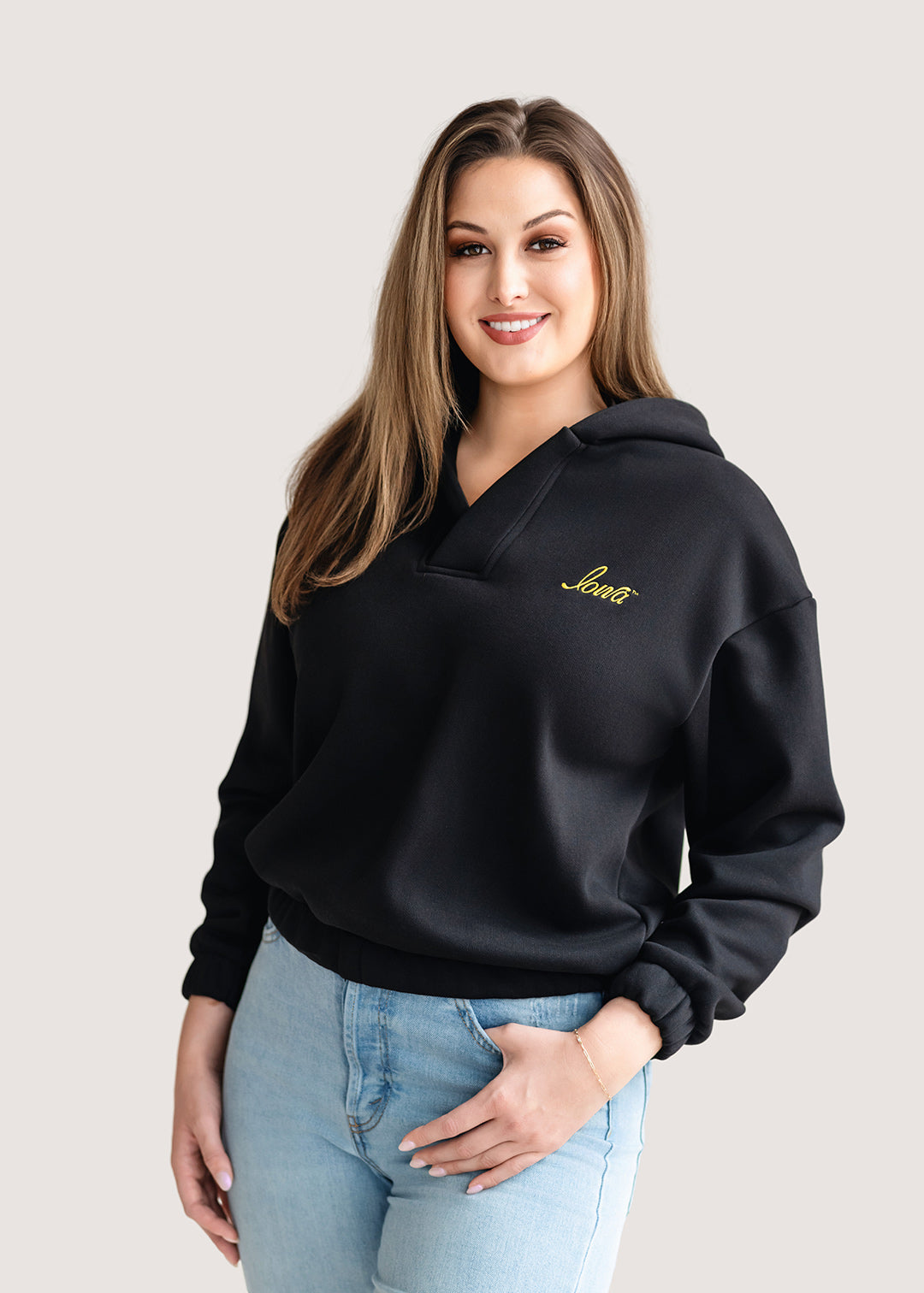 Woman wearing a black hoodie with a gold Iowa script logo.