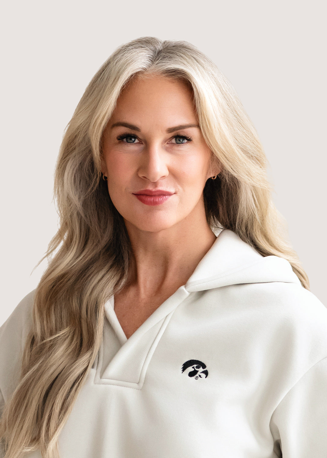 Woman wearing an ivory hoodie with a black Tigerhawk logo.