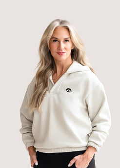 Woman wearing an ivory hoodie with a black Tigerhawk logo.
