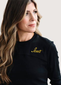 Woman wearing a long sleeve black shirt with a gold Iowa script logo.