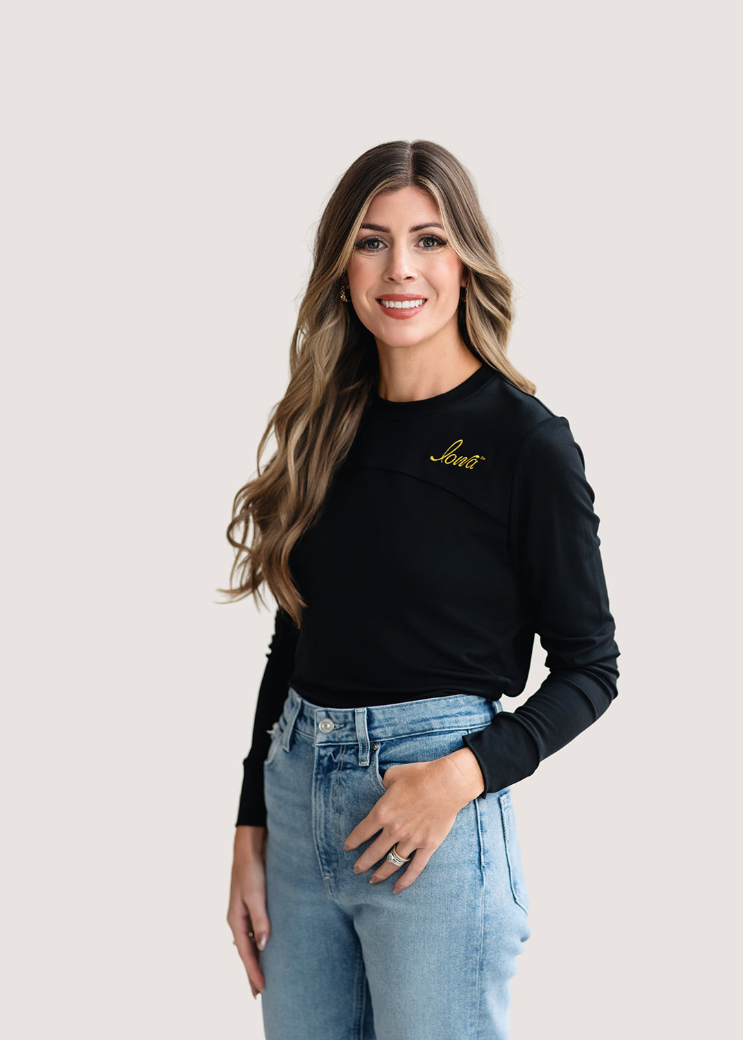 Woman wearing a long sleeve black shirt with a gold Iowa script logo.