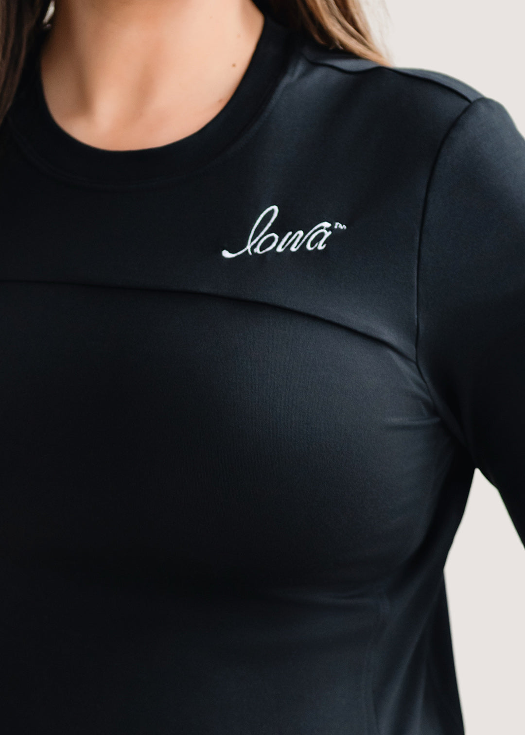 Woman wearing a long sleeve black shirt with a white Iowa script logo.