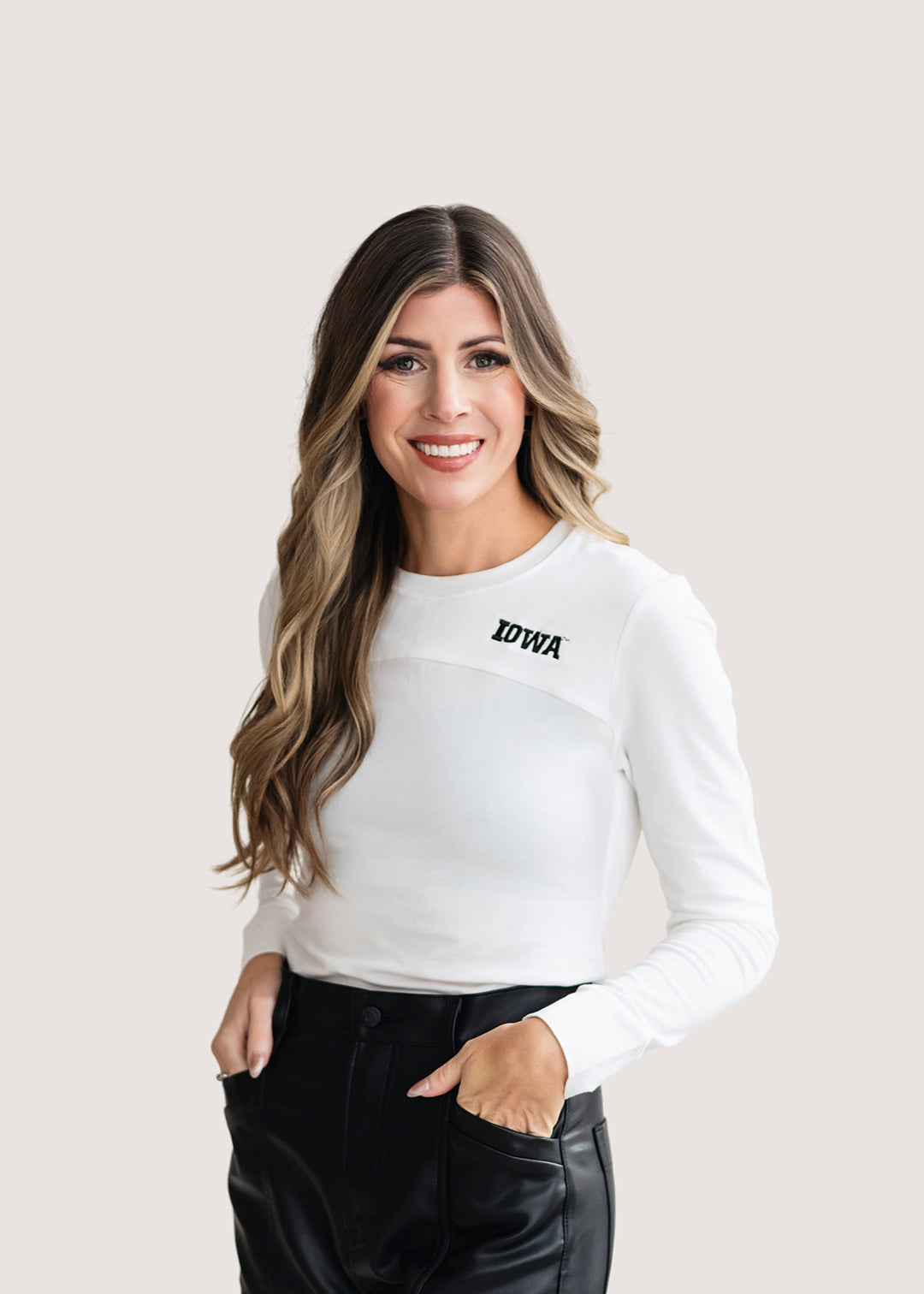 Woman wearing a long sleeve white shirt with a black University of Iowa logo.