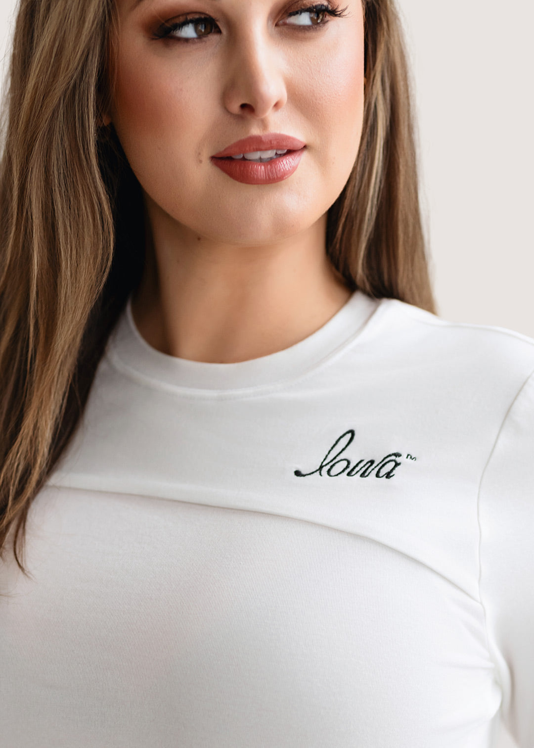 Woman wearing a long sleeve white shirt with a black Iowa script logo.