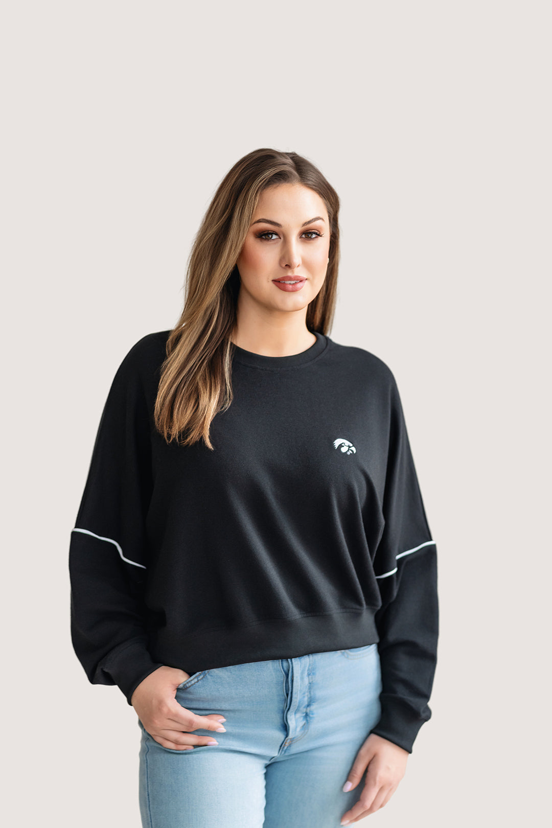 Woman wearing a black, drop shoulder sweatshirt with white trim and a white Tigerhawk logo.